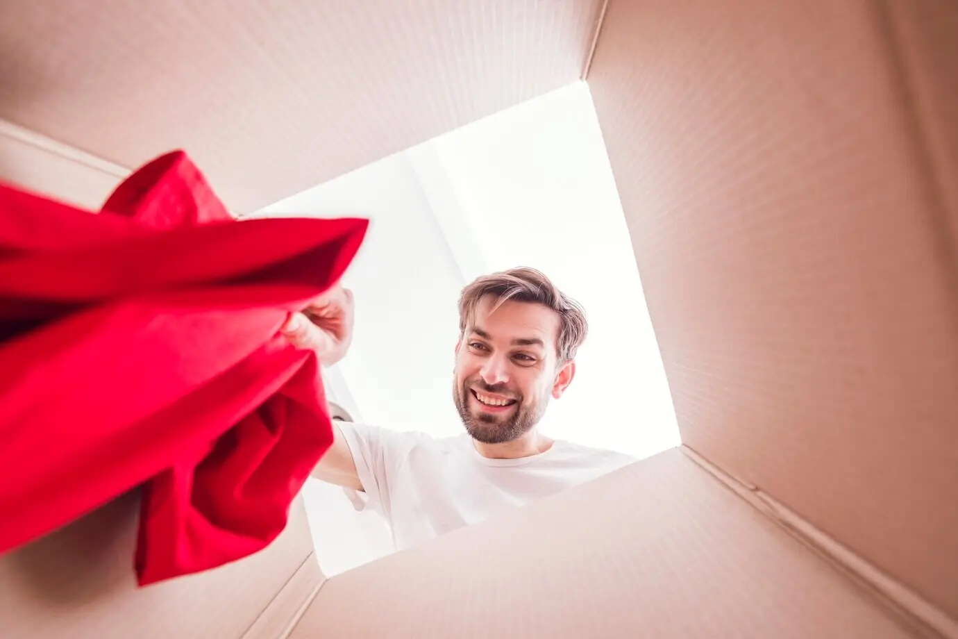 Вид изнутри со дна коробки на мужчину, держащего рубашку.